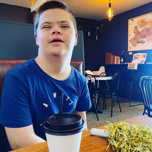 Kid with down sydrome chilling in a cafe — NDIS Provider on the Sunshine Coast, QLD